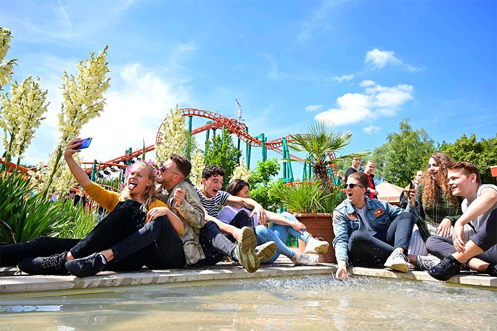 Freunde chillen vor der schwebenden Achterbahn Condor.